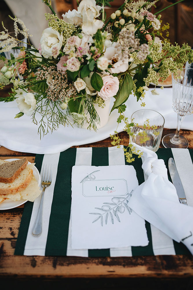 Dettaglio della mise en place con menu personalizzato e allestimento floreale al tavolo del ricevimento