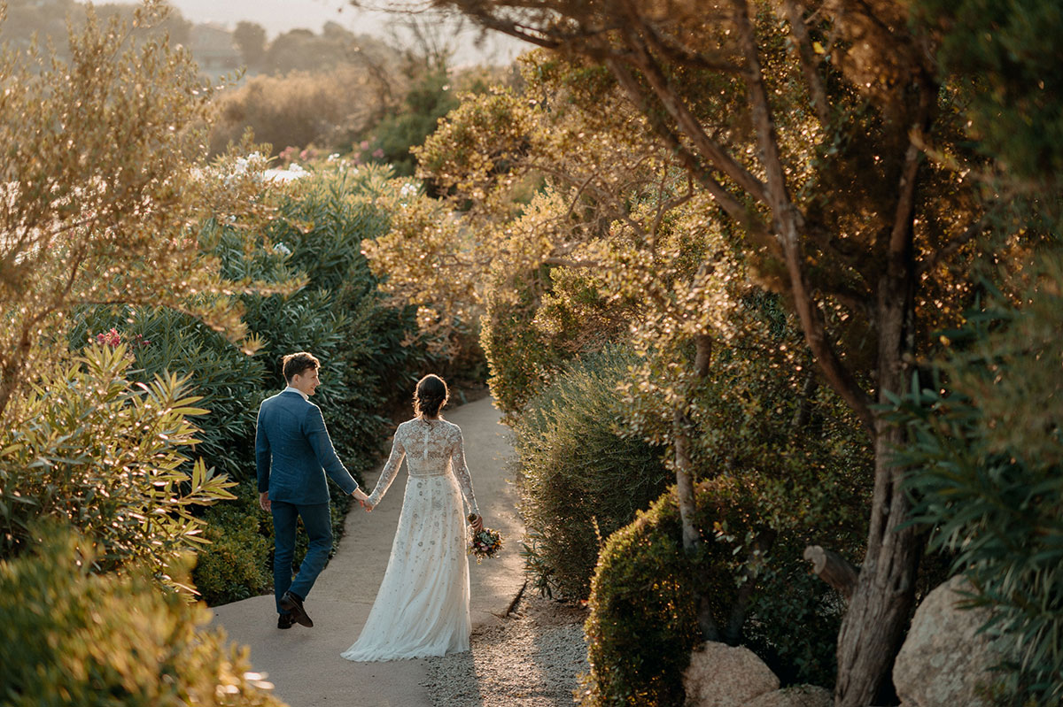Carlo e Julia camminano mano nella mano lungo un sentiero immerso nella natura sarda