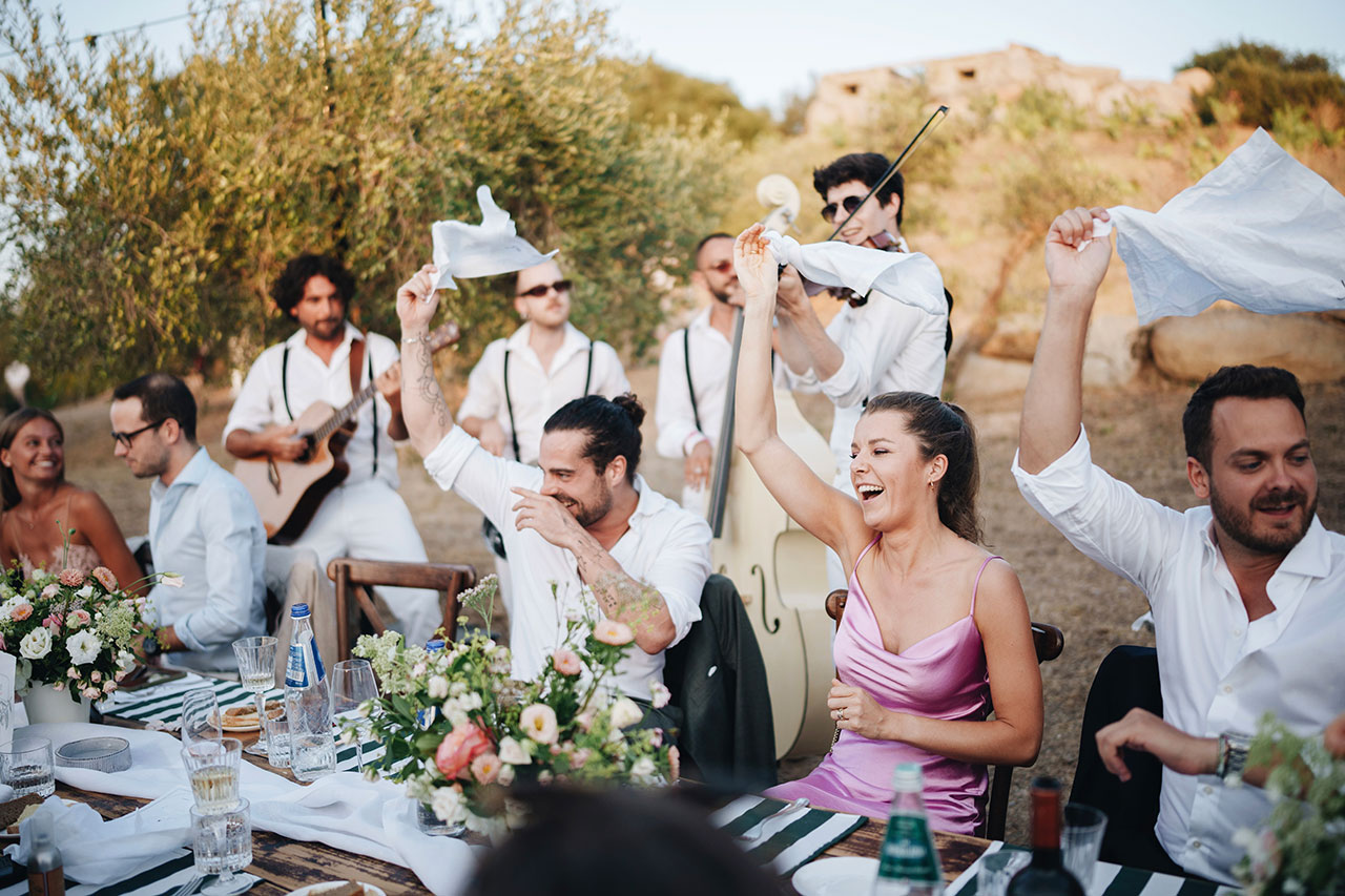 Invitati che festeggiano all’aperto immersi nella natura durante un ricevimento di matrimonio